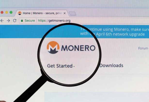 The logo of Monero (XMR) is seen through magnifying glass