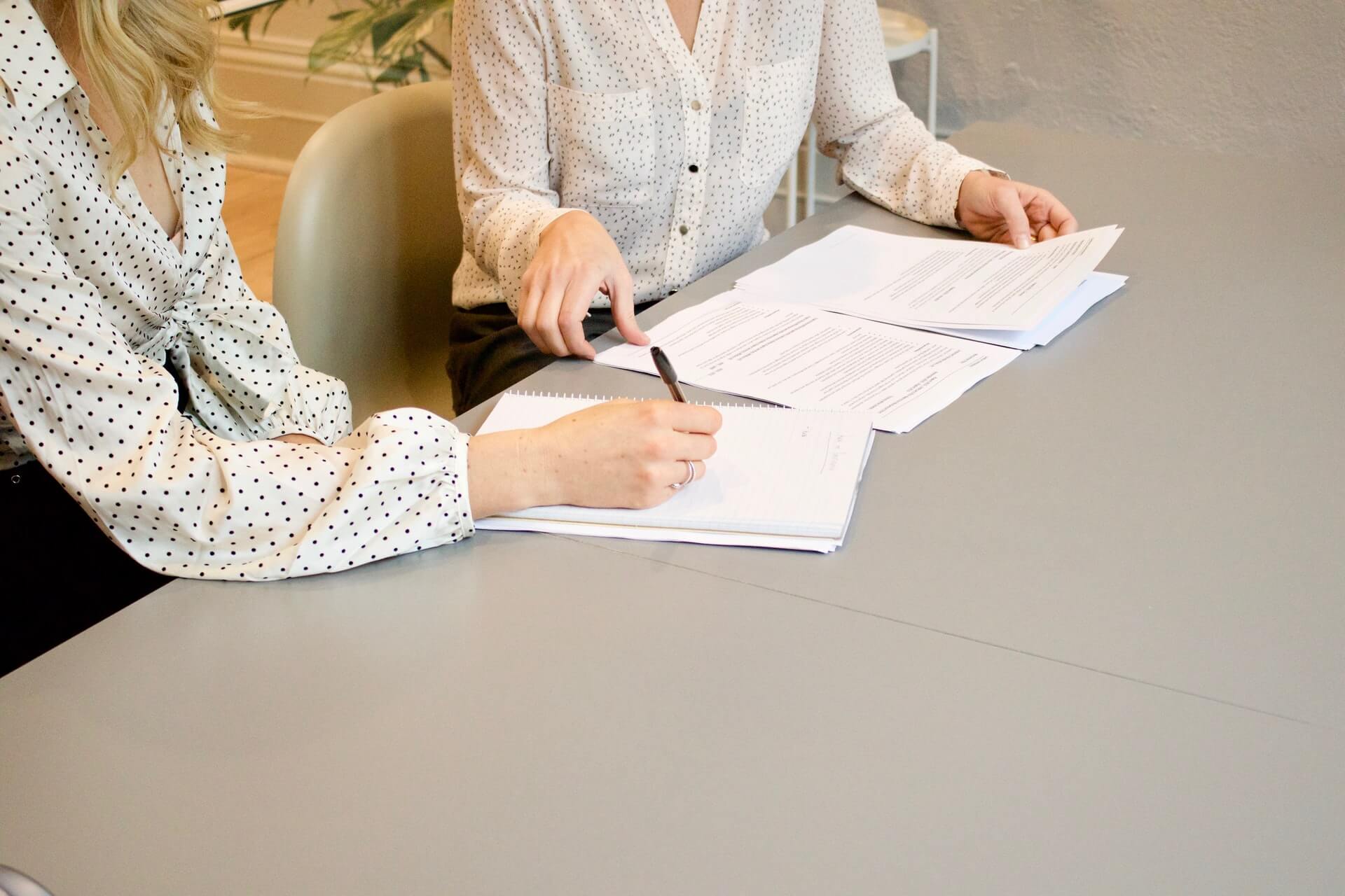 Image of women sitting next to each other behind a desk discussing a topic to depict the case study