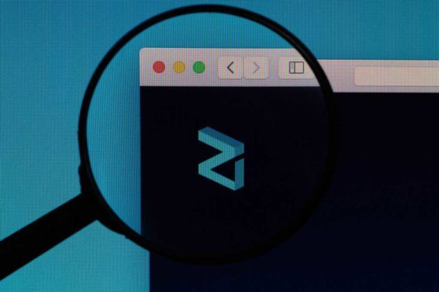 The logo of Zilliqa (ZIL) is seen through magnifying glass on the screen