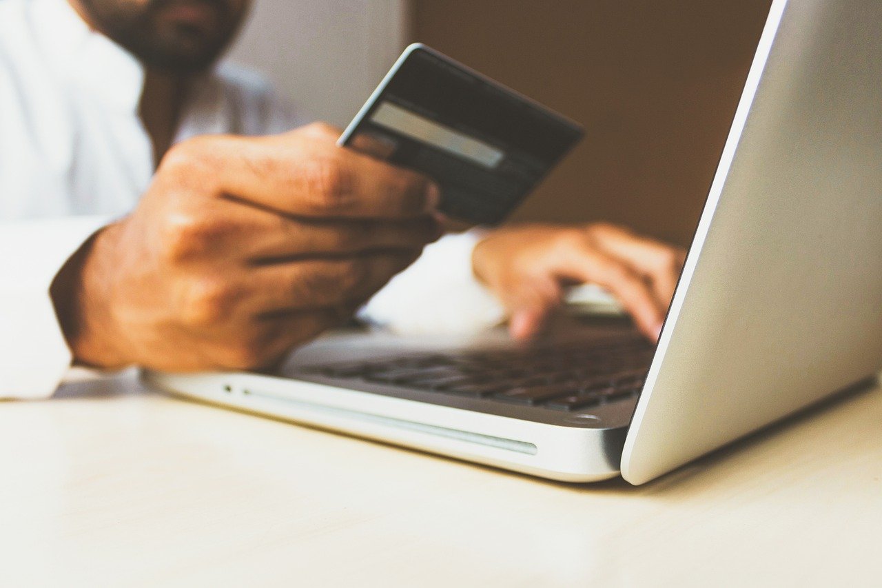 A man holding a credit card in front of a laptop to depict the idea of how to buy bitcoin in Nigeria