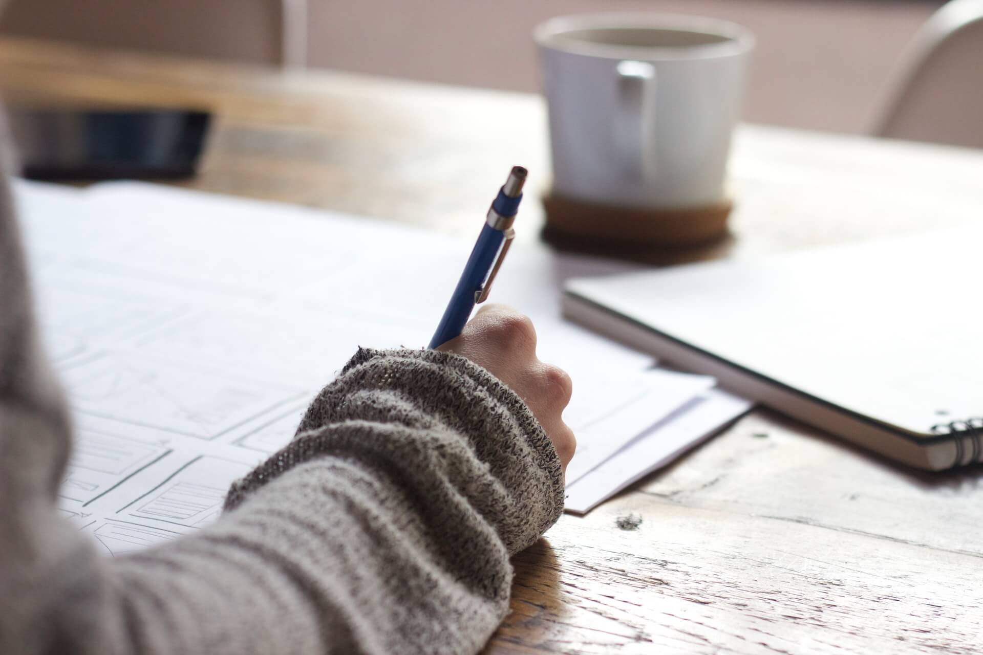 Image of a woman's hand writing on a piece of paper