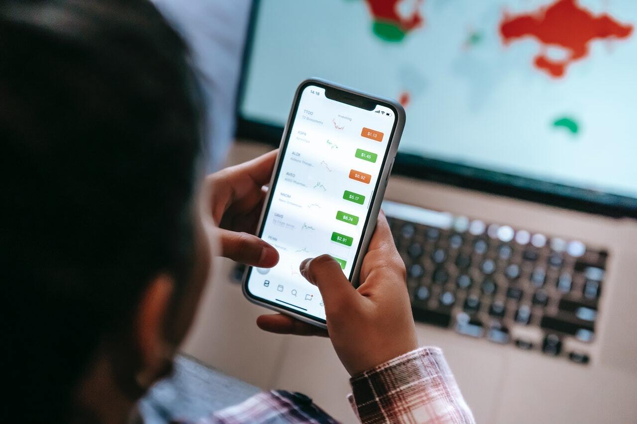 Image of a man holding a phone browsing price charts.