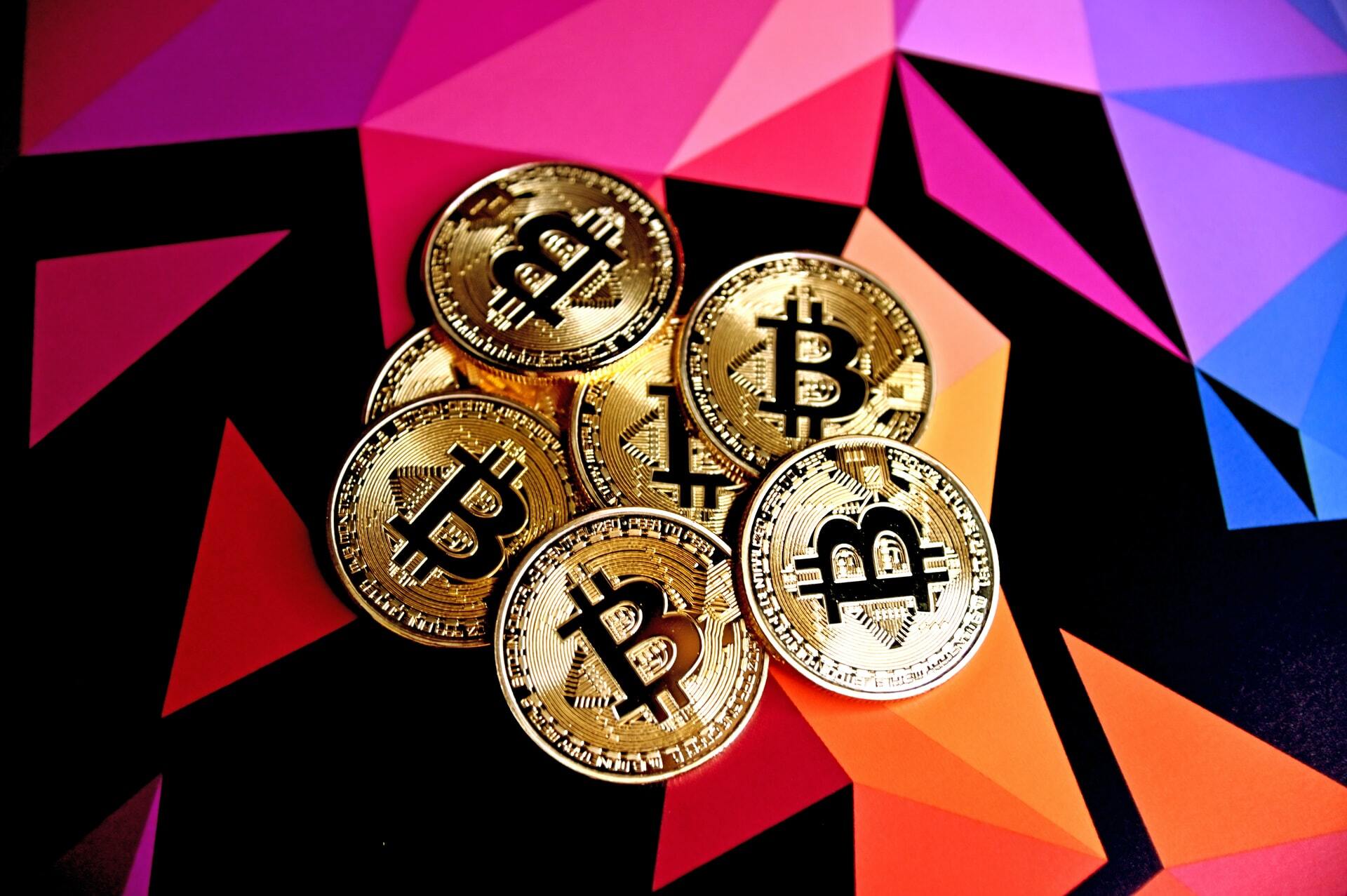 A pile of physical bitcoins placed on top of a colorful surface to illustrate the topic of what is cryptocurrency.