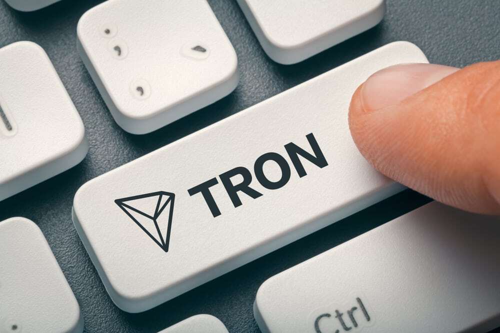 Finger pressing the enter button on a keyboard that says Tron. 