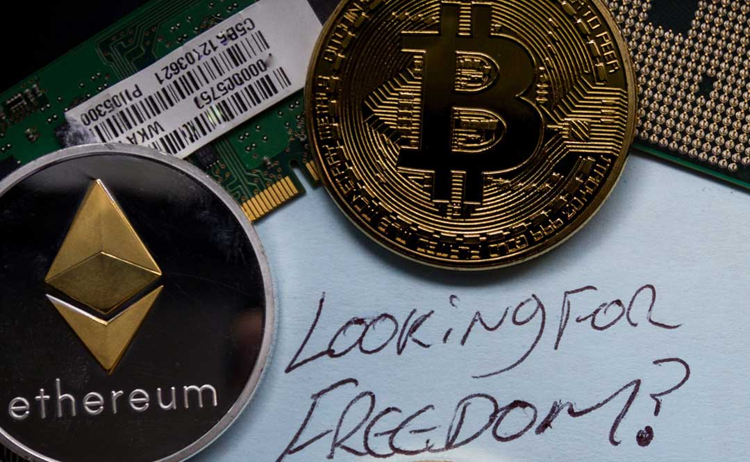 Bitcoin and Ethereum token are illustrated as physical coins with text "Looking for freedom?" written in a white paper