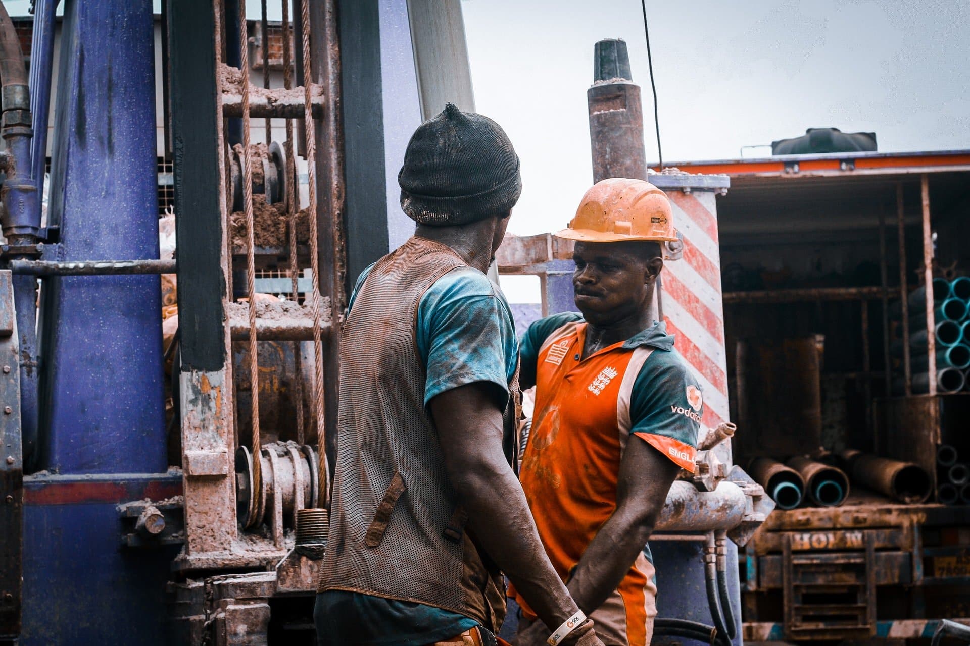 Workers standing beside a drilling machine