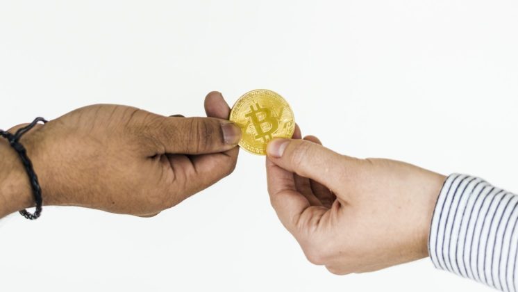 two-people-holding-a-bitcoin-coin-with-a-white-background two people holding a bitcoin coin with a white background in NZ