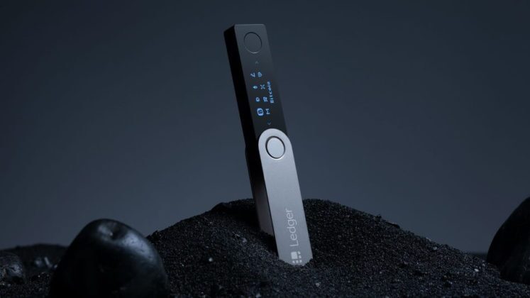 Ledger Nano X vertically placed on a pile of black sand with keylighting from above Ledger Nano X vertically placed on a pile of black sand with keylighting from above