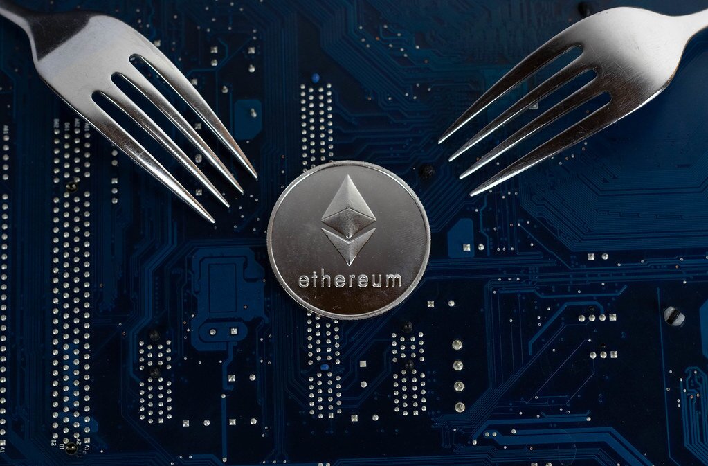 Two forks facing a physical Ethereum coin.