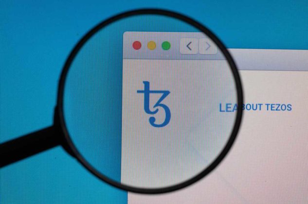 The logo of Tezos (XTZ) is seen through magnifying glass