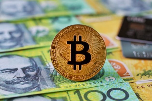 Bitcoin BTC physical gold coin on pile of Australian dollar bank notes AUD what is Bitcoin