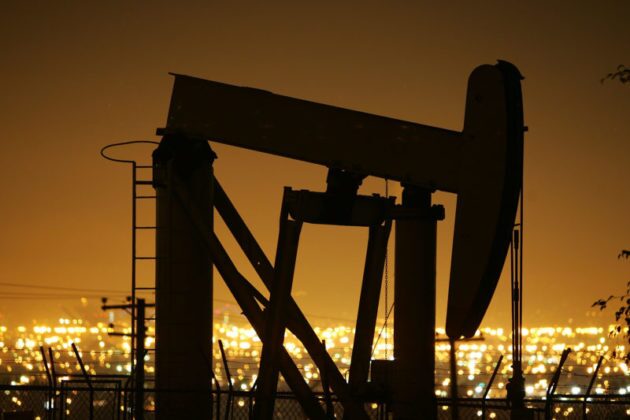 Oil pump at night with city lights in background