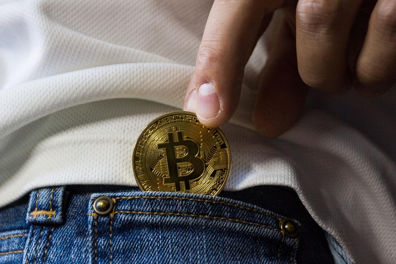 Picture of a bitcoin being put in the back pocket to illustrate crypto scam